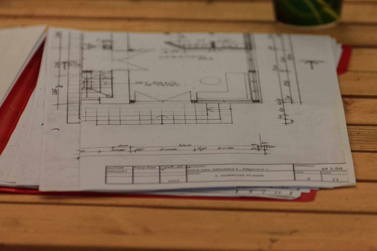 Planimetrie tecniche in scala con quote e cartiglio, appoggiate su un tavolo di legno