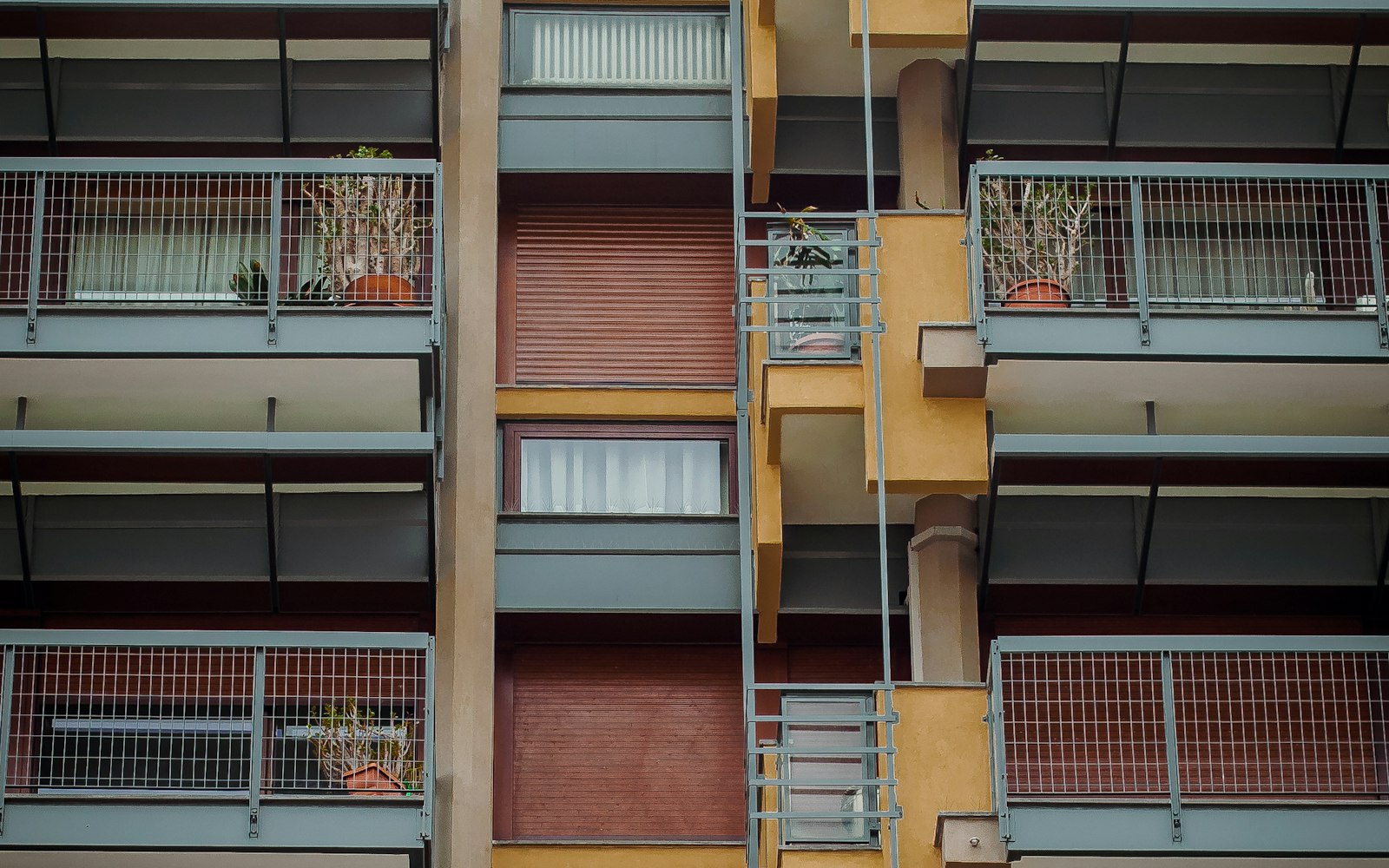 Facciata di un condominio residenziale con balconi, tapparelle e piante sui terrazzi